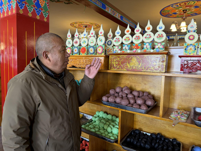 图为达瓦坚赞正在介绍店内的酥油花。记者 明吉 曹琳 摄