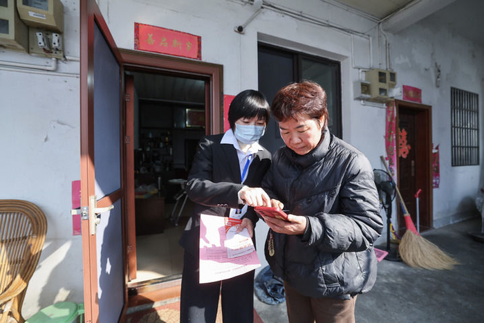 2025年12月18日，浙江省诸暨市东白湖镇事业综合服务中心的党员志愿者（左）上门“一对一”指导村民使用“浙里办”数字化平台办理业务。新华社记者 徐昱 摄