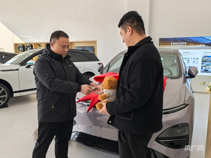 在新能源汽车4s店内,消费者张先生喜提爱车(央广网记者 刘佳音 摄)