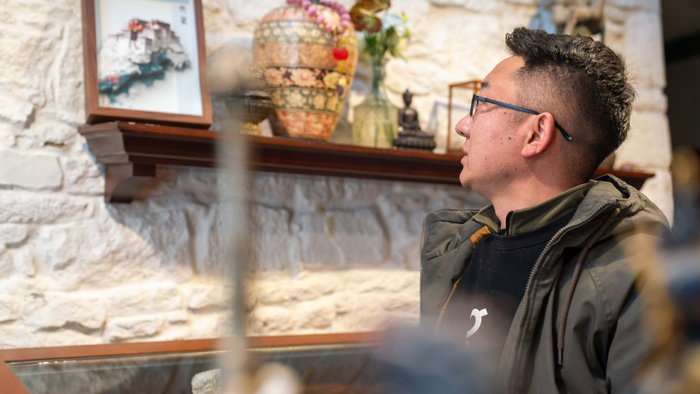 彭毛才让在位于拉萨市八廓街的店铺内介绍纸雕的布达拉宫。记者 欧珠次仁 摄