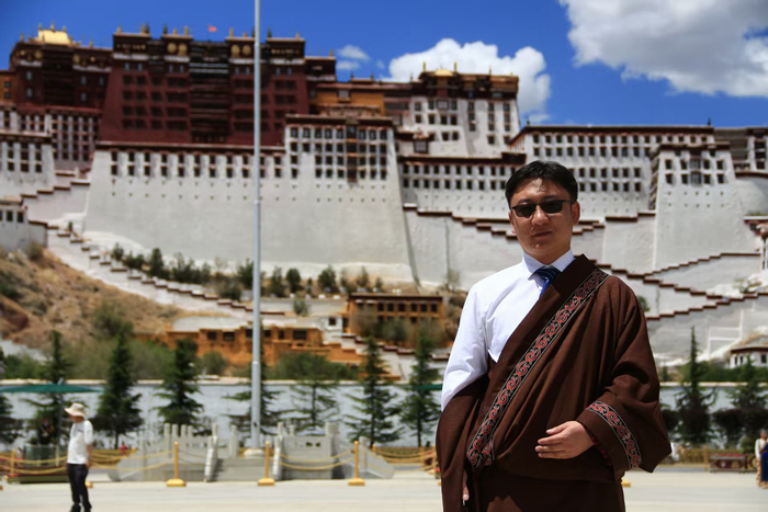 彭毛才让从西藏大学硕士毕业后在布达拉宫前拍照留念。（受访者供图）