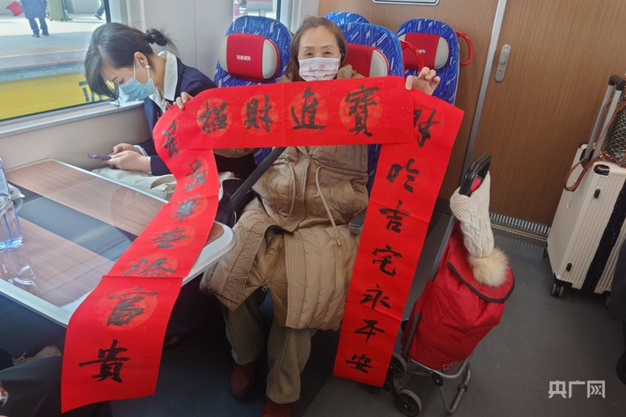 旅客展示开封站活动书法家现场书写的春联（央广网记者  夏莎  摄）