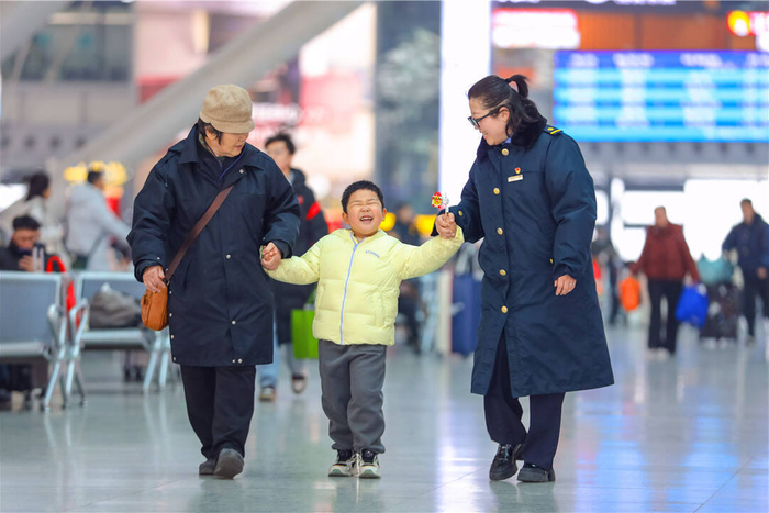2月2日，在青岛火车北站，工作人员帮助旅客乘车出行。张鹰 摄