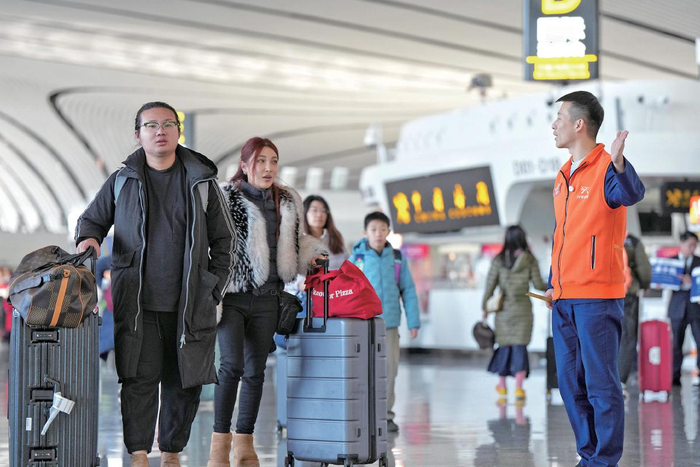 2月2日，北京大兴国际机场，志愿者为旅客提供问询指导。摄影/新京报记者 陶冉