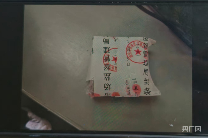 工作人员向记者展示挂坠封存照片（央广网记者 郑少纯 摄）