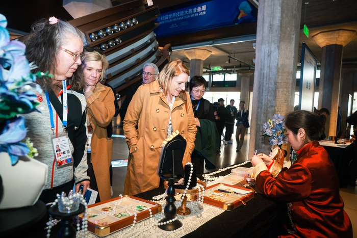 外国嘉宾在中国非遗技艺展示摊位前驻足欣赏