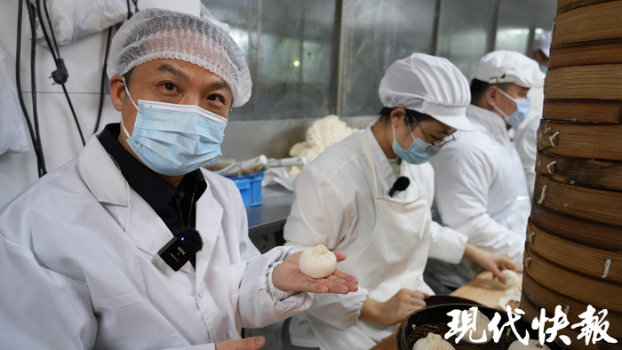 记者（左）在周慧敏帮助下试着包了一个包子