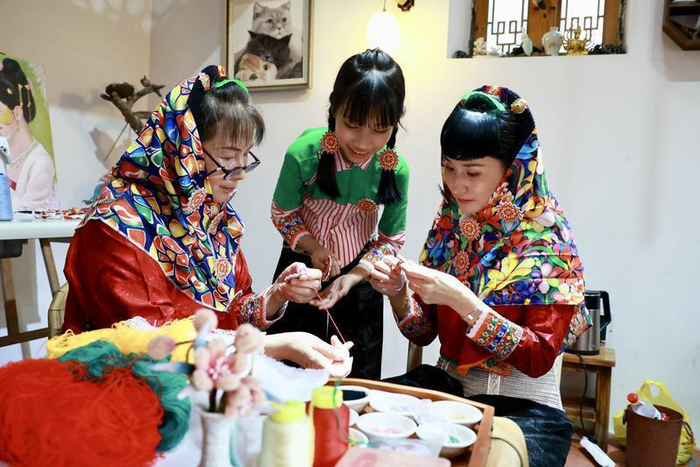 张美玲（右）和她的母亲、女儿在学习刺绣针法。