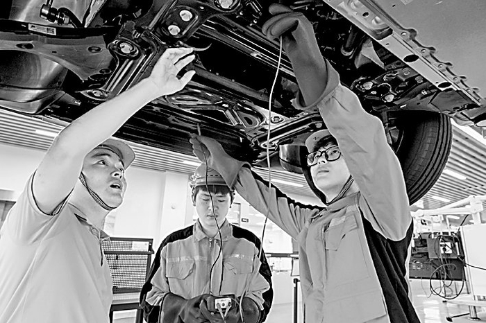 安徽省芜湖机械工程学校实训基地，学生在老师的指导下学习新能源汽车维修。肖本祥摄/光明图片