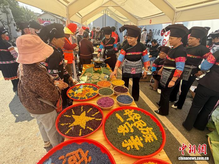 春节前夕，云南文山砚山县平远镇年货街上人头攒动，五色花米饭、面蒿粑粑等各民族特色小吃吸引不少赶集民众驻足品尝。陆希成 摄