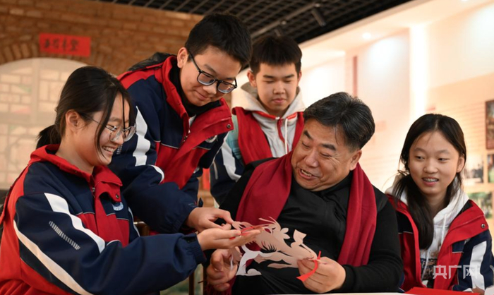 段建珺手把手纠正学生们的剪纸手法（央广网发  贝赫  摄）