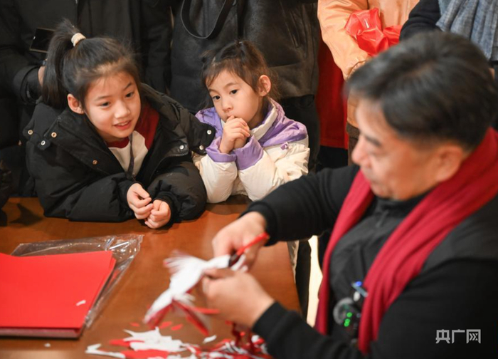 两名儿童在观看剪纸创作（央广网发  马金瑞  摄）