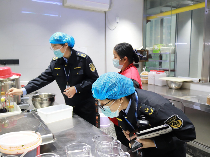 执法人员在餐厅后厨核查食材配料信息。八步区市场监管局供图