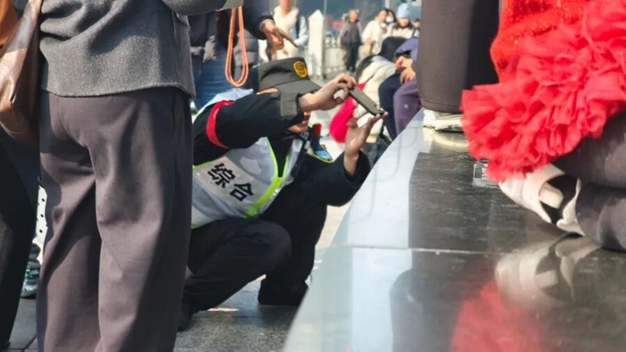 付大哥蹲下为市民寻找好机位。杜晨薇 摄