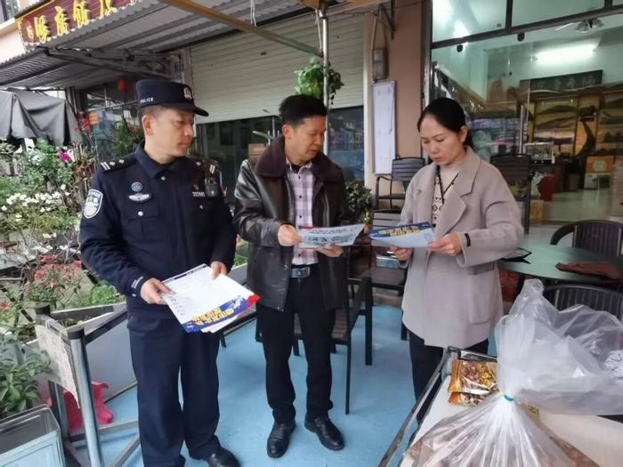 周梅初（中）和民警一起群众发放法治宣传单