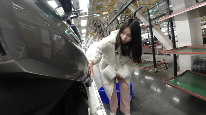 重庆财经学院网络与新媒体专业学生蒲靖恬正在给电动车贴膜。