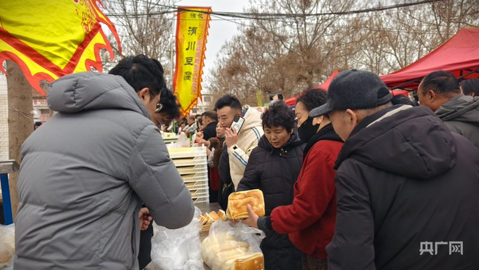 游客在买洧川锅盔、豆腐等美食（央广网记者  郝振青  摄）
