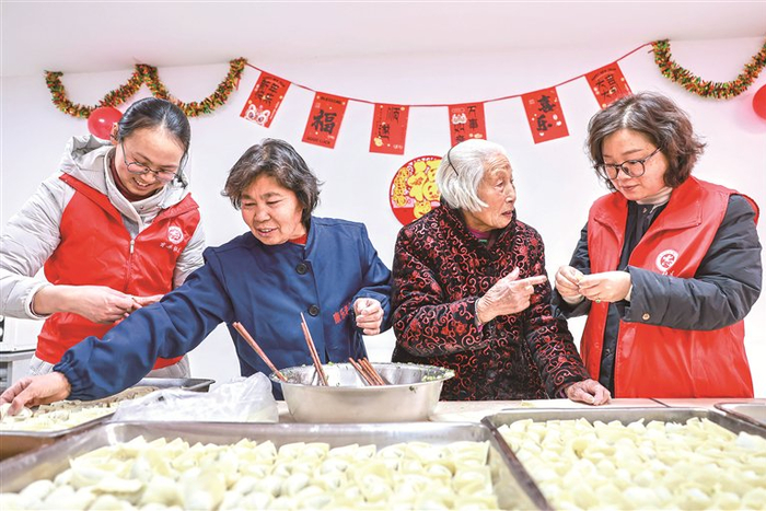 在江苏省泰兴市济川街道康乐老年公寓内，商井社区志愿者与老人们一起包饺子。 新华社发 顾继红 摄