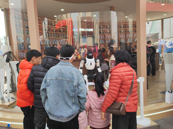 在成都春熙路，市民游客驻足观看店内售卖的人形机器人。新华社记者 张海磊 摄