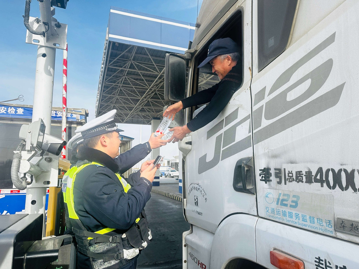 交警正在向过往车辆司机赠送纯净水。李萍 摄