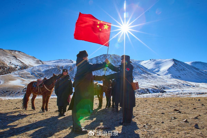 图为卡昝河边境警务站戍边民警接过五星红旗，组成巡边踏查分队出发。​