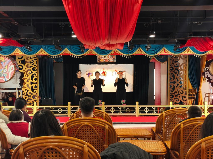 　　三位演出者正在向台下观众展示表演时用到的皮影。新华社记者 张申博 摄