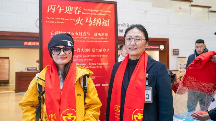 2月17日，西藏博物馆为50名属马的市民游客赠送喜庆围巾。这是游客谢女士（左）领取喜庆围巾后戴在脖子上。记者 欧珠次仁 摄