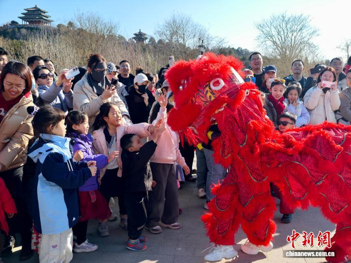 北京景山公园新春游园活动上，观众和舞狮演员互动。公园供图