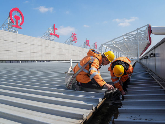 2月17日，中国铁路上海局集团有限公司上海房建公寓段的工作人员在上海虹桥火车站的屋面钢结构上清理垃圾。新华社记者 丁汀 摄