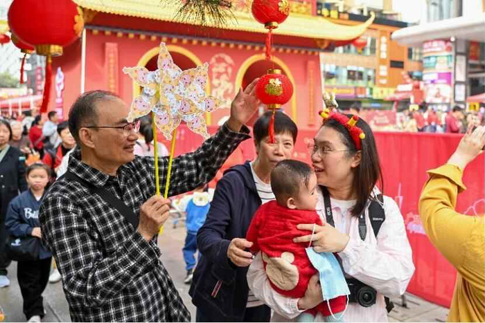 2026年2月13日，已有百年历史的广州西湖花市开市迎客。图为市民手持风车逛花市迎新春。中新社记者 陈骥旻 摄