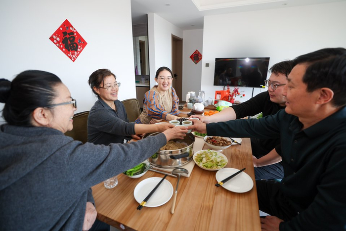 2月18日大年初二，牛佩瑶（左三）和家人们在家一起吃团圆饭。一家人举起茶杯碰杯欢庆。人民日报记者 张武军摄