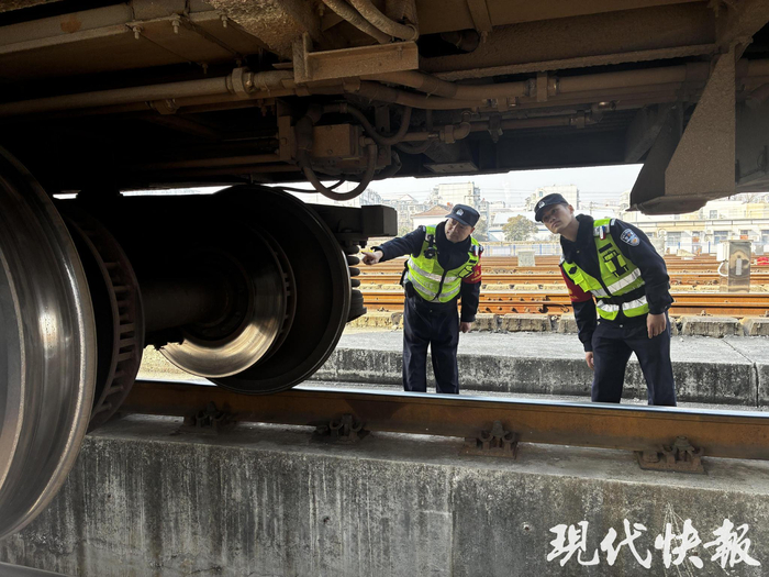 王强和同事对车底及重要部位进行安全防范检查