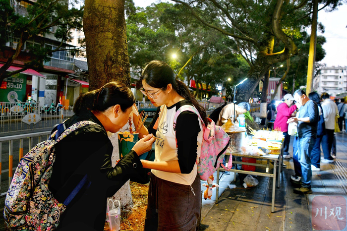 游客在夜市里品尝美食。