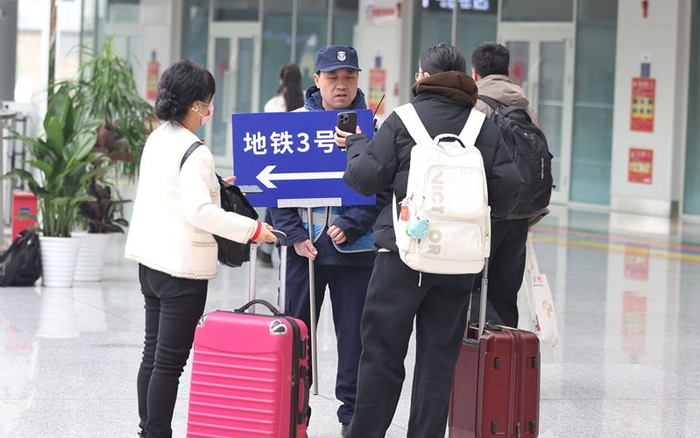 2月21日，北京朝阳站，工作人员指引旅客换乘地铁3号线。新京报记者 王贵彬 摄