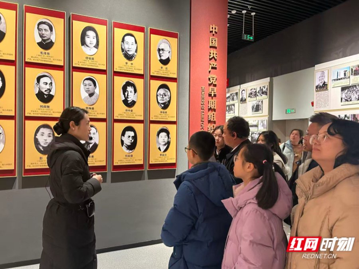 在中国共产党湖南历史展览馆展厅里，家长带着孩子们驻足观看、认真聆听。