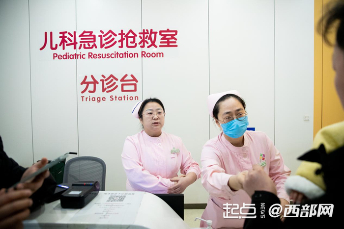 护士正在分诊台为患儿家长答疑、登记。