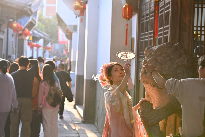 2月21日，在福州三坊七巷传统街区，头戴簪花的女士在拍照 图片来源：新华社记者 姜克红 摄