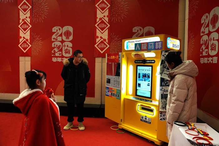 在克拉玛依市美术馆，当地孩子在“喜提头条”设备前拍照，领取她登上头条的“报纸”。崔文娟摄