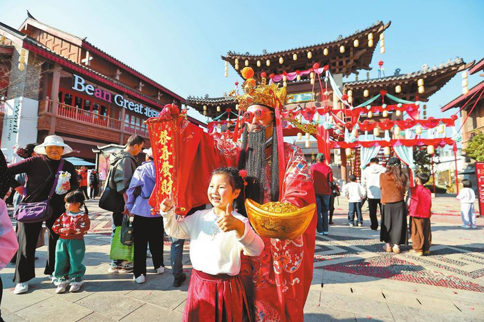 游客在昆明融创文旅城与“财神”合影。 本报记者 陈飞 摄