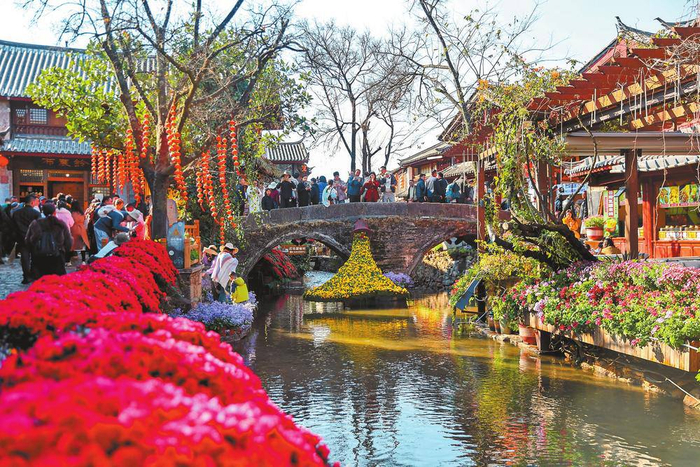 丽江古城鲜花盛开，游客徜徉于青石板路上。 本报记者 陈飞 摄