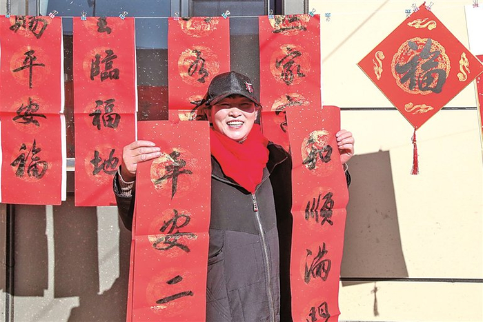 村民在榆中县灾后重建集中搬迁入住活动现场领取春联。新华社发