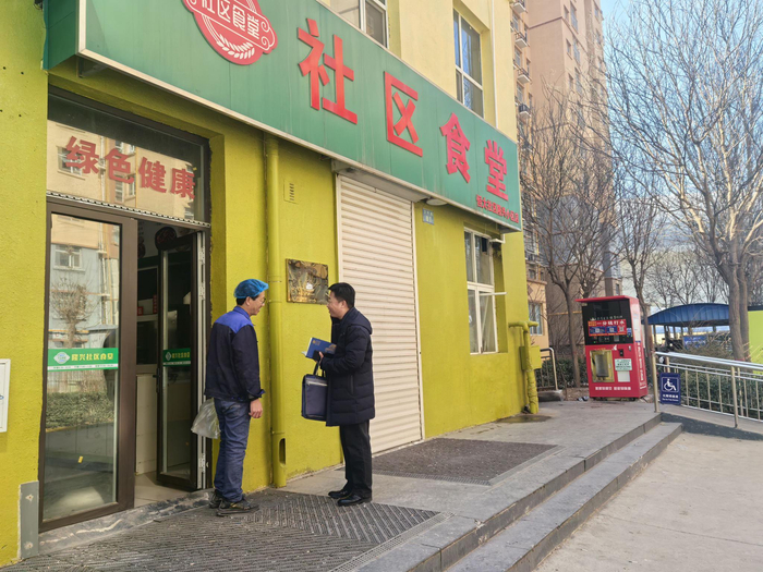 隆兴小区社区食堂工作人员向记者介绍春节档期安排。张强/摄