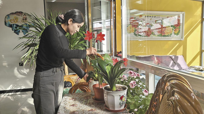 赵国梅正在欣赏家里的花。杨红霞 摄