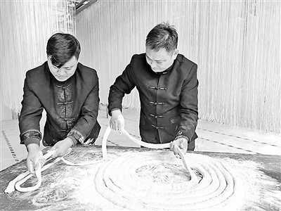 潢川空心贡面制作技艺省级非遗代表性传承人刘来旺（右）和儿子刘虹蕾在制作贡面。    刘力娜摄