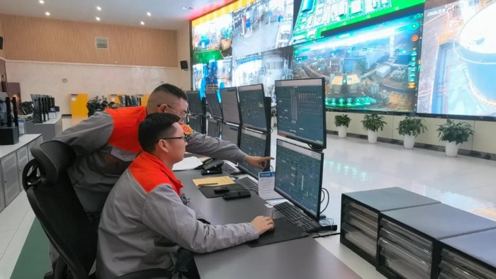 彭大鹏（左）正指导员工在屏幕上观察生产参数