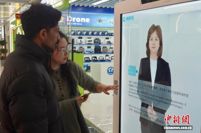 2月28日，浙江义乌，中外客商在店铺门前与多语种数字人对话。董易鑫 摄