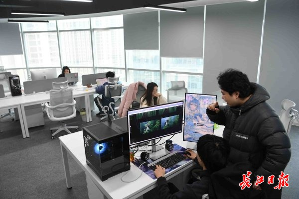 武汉灵境引擎科技有限公司创始人张奥（站立者）和团队成员在一起办公。 长江日报记者高勇 摄