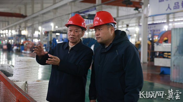 宁小五（左）在明达线缆集团有限公司生产车间和工作人员进行交流沟通。通讯员 孙亚伟 摄