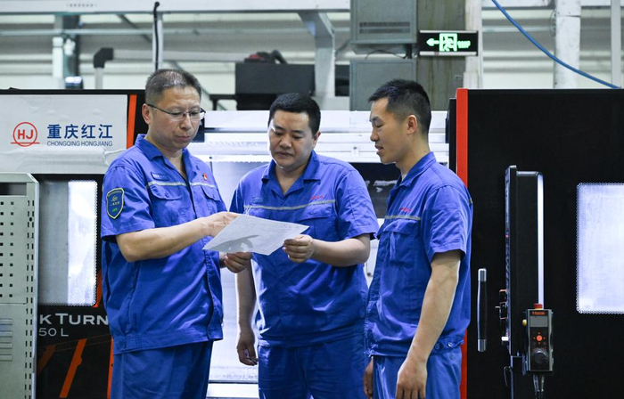 2025年5月23日，傅国涛（左一）在重庆红江机械有限责任公司生产车间与同事交流。新华社记者 王全超 摄