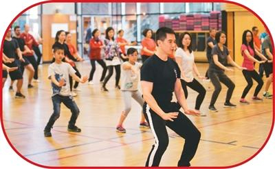 谭振江（前）在温哥华“快乐山”社区中心举办功夫养生讲座，带领参与者体验蔡李佛拳。受访者供图